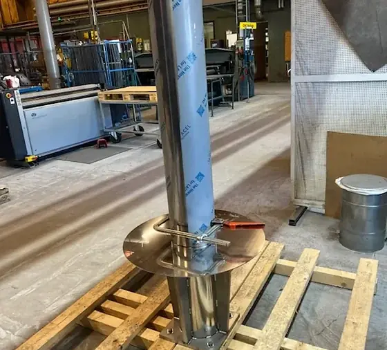 Polerad rostfri kon står upprätt på pall i verkstaden under arbetet med Projekt Droppen